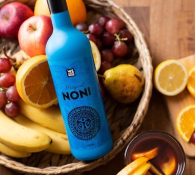 Noni juice bottle surrounded by fresh tropical fruits