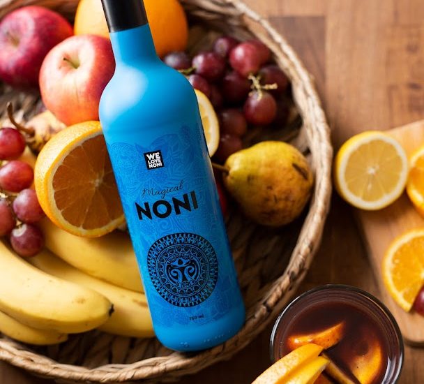 Noni juice bottle surrounded by fresh tropical fruits